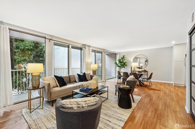 living room with a healthy amount of sunlight, light wood-type flooring, and baseboards