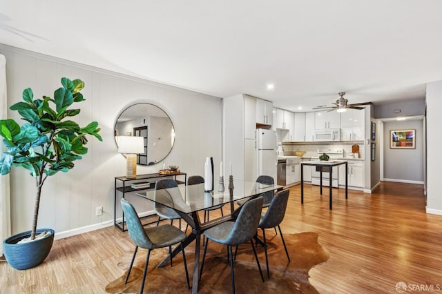 dining space featuring a ceiling fan, light wood-type flooring, and baseboards