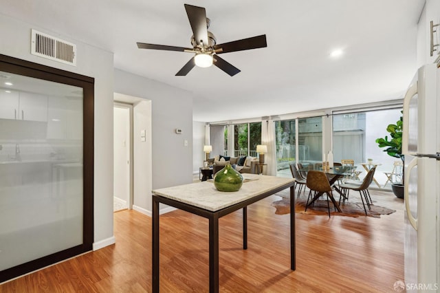 dining space with ceiling fan, light wood finished floors, visible vents, and baseboards