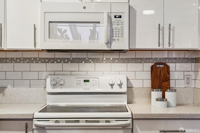 kitchen with white appliances, backsplash, and white cabinetry