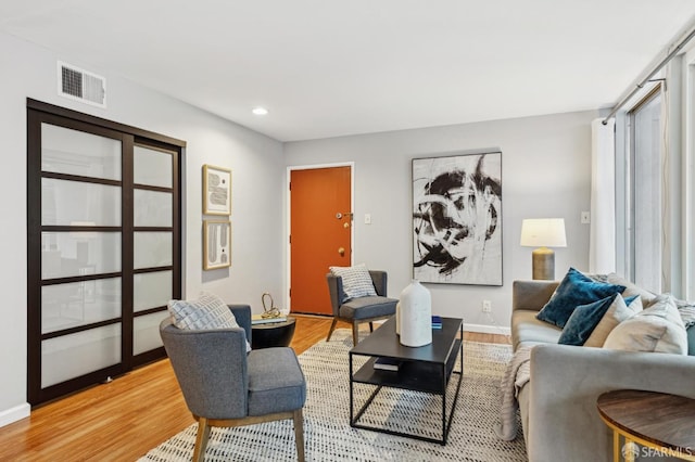 living area featuring baseboards, light wood-type flooring, visible vents, and recessed lighting