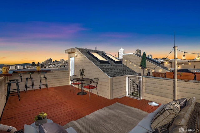 deck at dusk with exterior bar and an outdoor hangout area