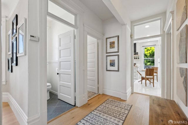 hall with light wood-style floors, baseboards, and recessed lighting