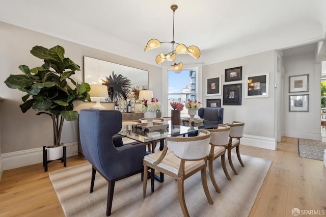 dining area featuring a chandelier, light wood-style floors, and baseboards