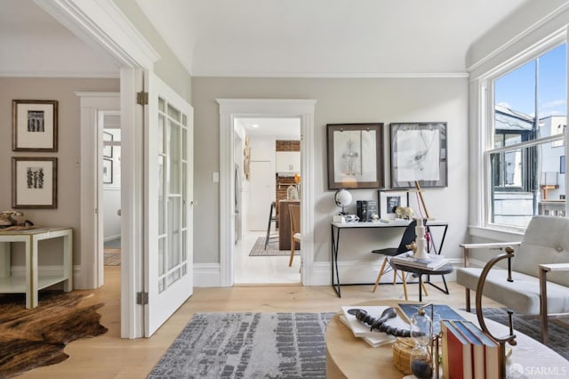 sitting room with healthy amount of natural light, wood finished floors, ornamental molding, and baseboards