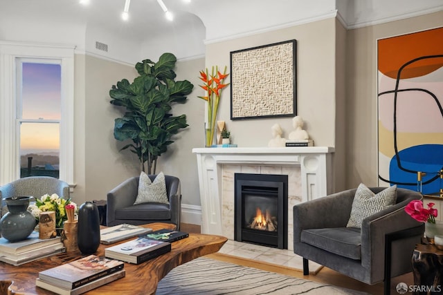 living area featuring a tiled fireplace and crown molding