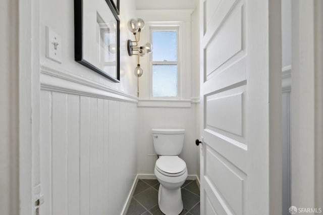 bathroom featuring tile patterned flooring, toilet, wainscoting, and baseboards