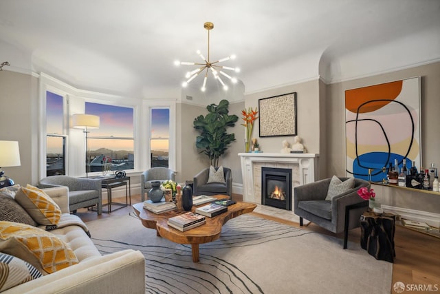 living area featuring a chandelier, a fireplace, wood finished floors, and ornamental molding