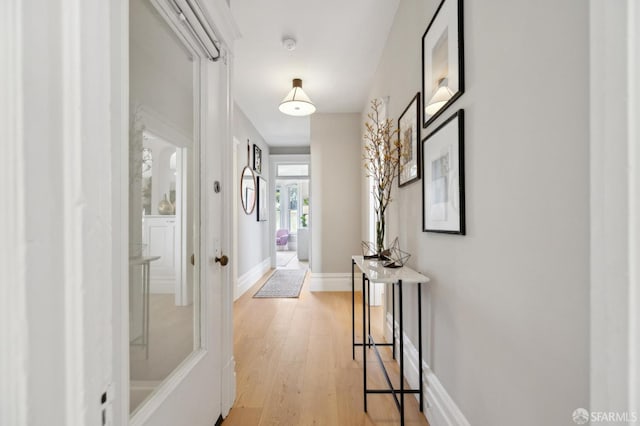 hall featuring light wood-style flooring and baseboards