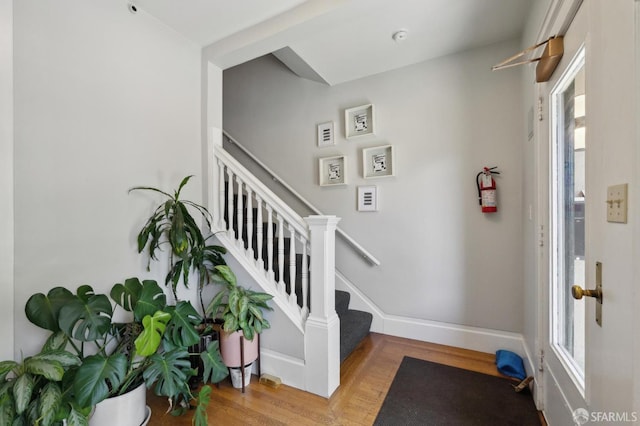 foyer entrance with wood finished floors, stairs, healthy amount of natural light, and baseboards