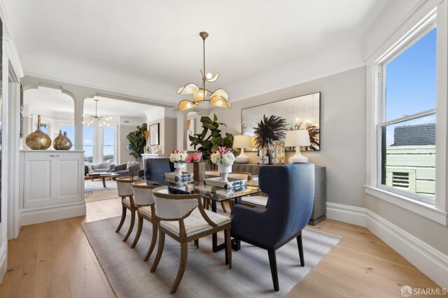 dining space featuring a chandelier, light wood-style flooring, and baseboards