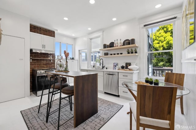 kitchen featuring a sink, white cabinetry, stainless steel appliances, a breakfast bar area, and recessed lighting