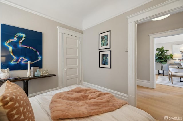 bedroom featuring wood finished floors, crown molding, and baseboards
