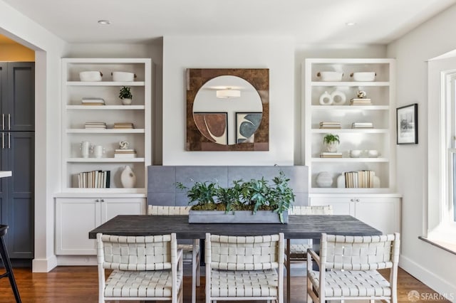 dining space featuring dark wood-type flooring and built in features