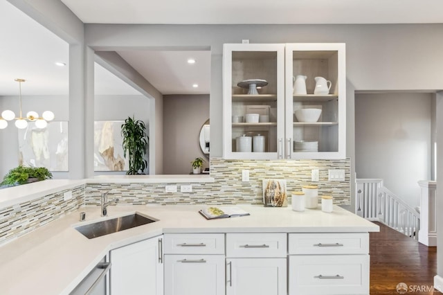 kitchen with tasteful backsplash, sink, pendant lighting, and white cabinets