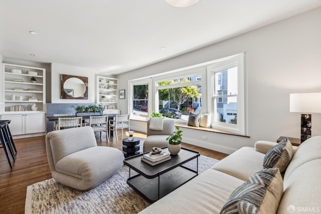 living room with dark hardwood / wood-style floors and built in shelves