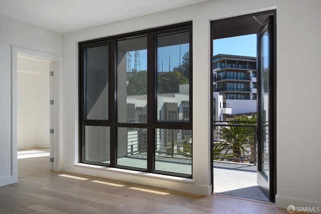 doorway with a wealth of natural light, baseboards, and wood finished floors