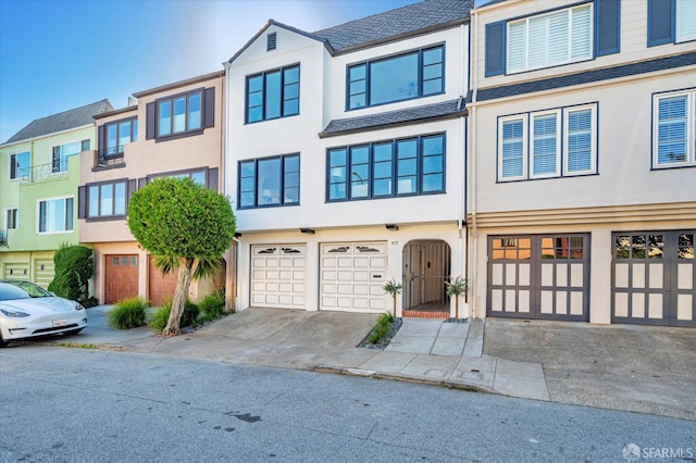 townhome / multi-family property with a garage, driveway, and stucco siding