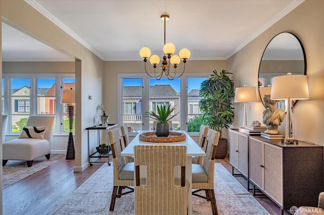 dining space with light wood finished floors, a notable chandelier, crown molding, and baseboards