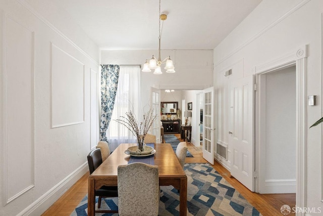 dining room with baseboards, a chandelier, and wood finished floors