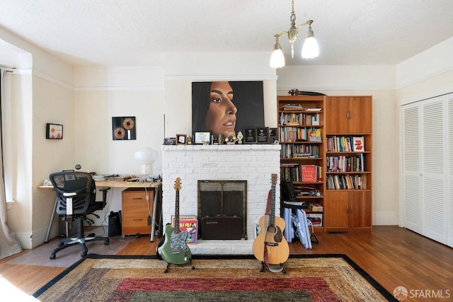 living area with a textured ceiling, a fireplace, baseboards, and wood finished floors