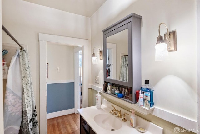 full bath with curtained shower, wood finished floors, vanity, and baseboards