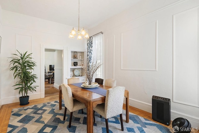 dining room with a chandelier, baseboards, and light wood finished floors