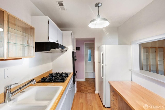 kitchen with under cabinet range hood, a sink, visible vents, white cabinets, and black appliances