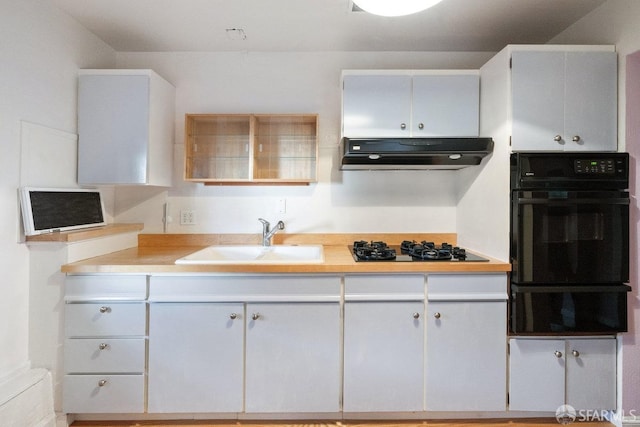 kitchen featuring under cabinet range hood, light countertops, black appliances, a sink, and a warming drawer