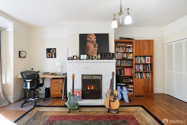 living area with a textured ceiling, a fireplace, wood finished floors, and baseboards