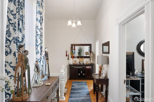 hallway featuring light wood-style floors and a notable chandelier