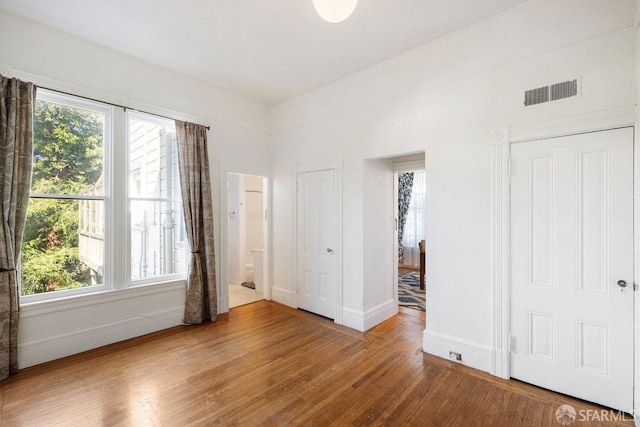 unfurnished bedroom featuring wood finished floors, visible vents, and baseboards