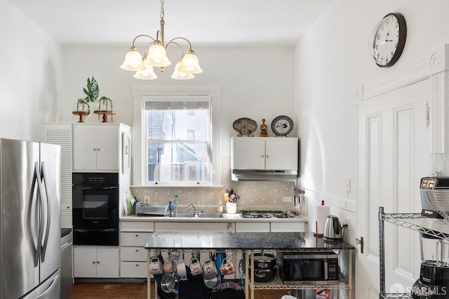 kitchen with backsplash, a notable chandelier, stainless steel appliances, under cabinet range hood, and a sink