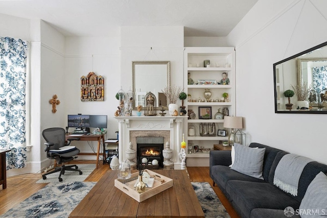 living area featuring built in shelves, a fireplace, and wood finished floors