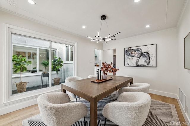 dining room with a notable chandelier, ornamental molding, and light hardwood / wood-style floors