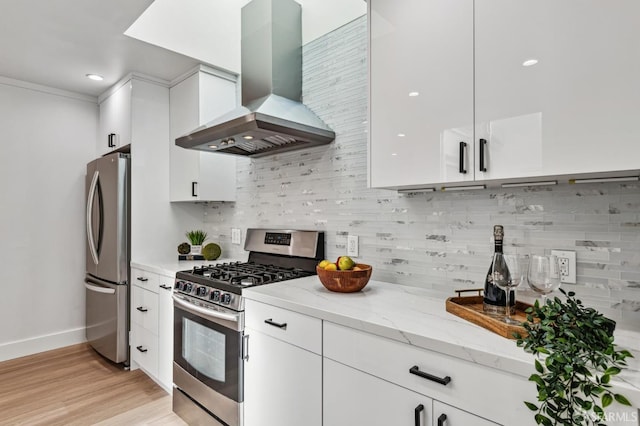 kitchen featuring white cabinetry, tasteful backsplash, stainless steel appliances, light stone countertops, and wall chimney range hood