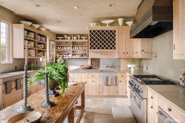 kitchen featuring light brown cabinetry, high end stainless steel range oven, and custom exhaust hood