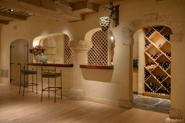 wine room featuring beam ceiling, wooden ceiling, and wood-type flooring