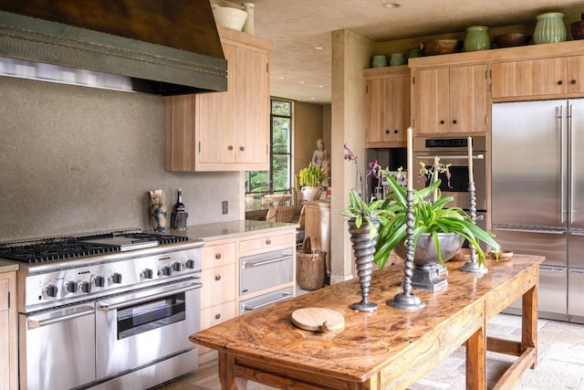 kitchen with light brown cabinetry, exhaust hood, and premium appliances