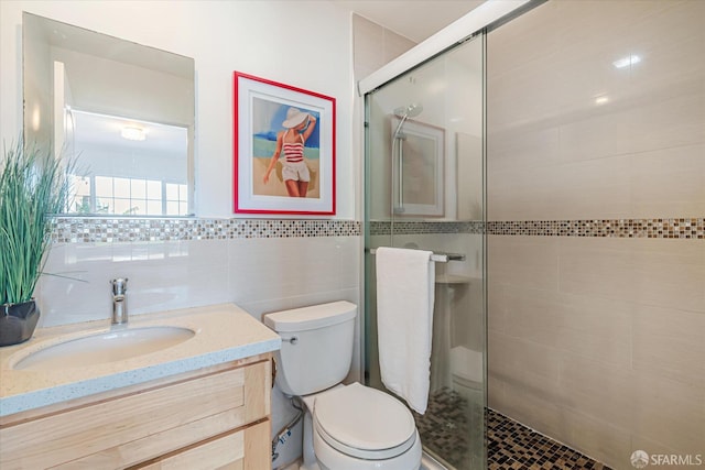 bathroom with walk in shower, vanity, toilet, and tile walls