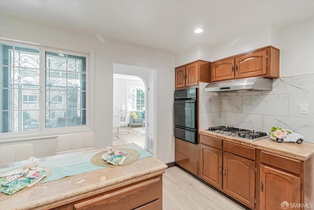 kitchen featuring oven, decorative backsplash, plenty of natural light, and stainless steel gas cooktop