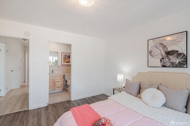 bedroom featuring ensuite bath, hardwood / wood-style floors, and sink