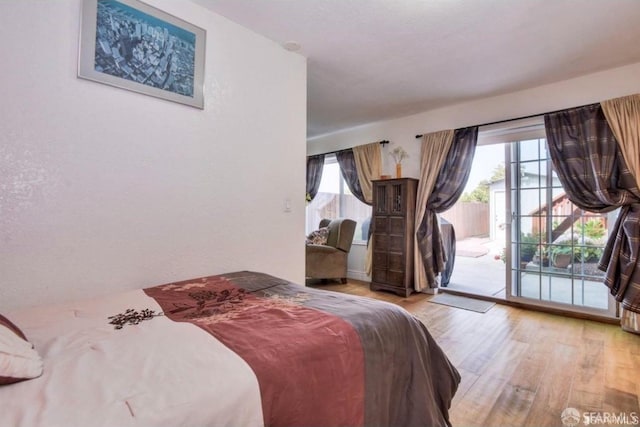 bedroom with access to exterior, light hardwood / wood-style flooring, and multiple windows