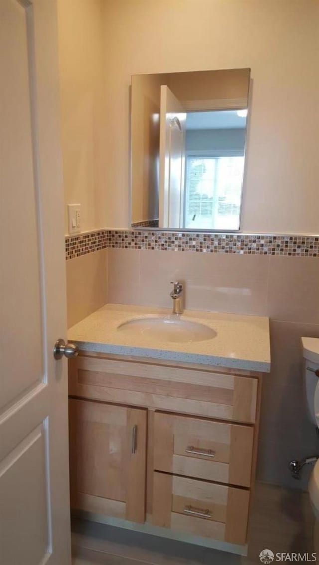 bathroom featuring vanity, tile walls, and toilet