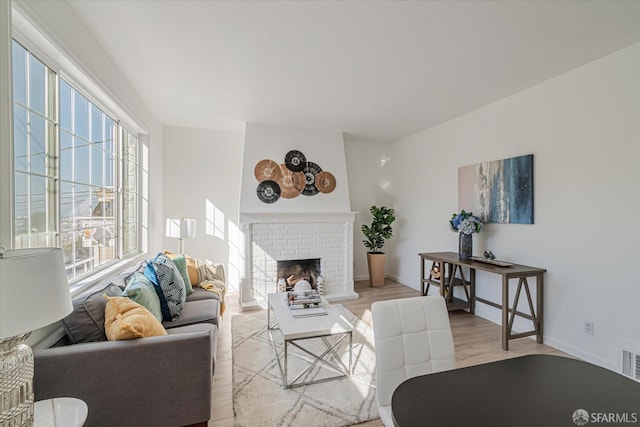 living room with light hardwood / wood-style floors and a brick fireplace