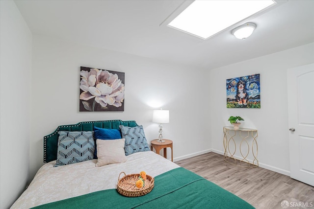 bedroom with a skylight and hardwood / wood-style flooring