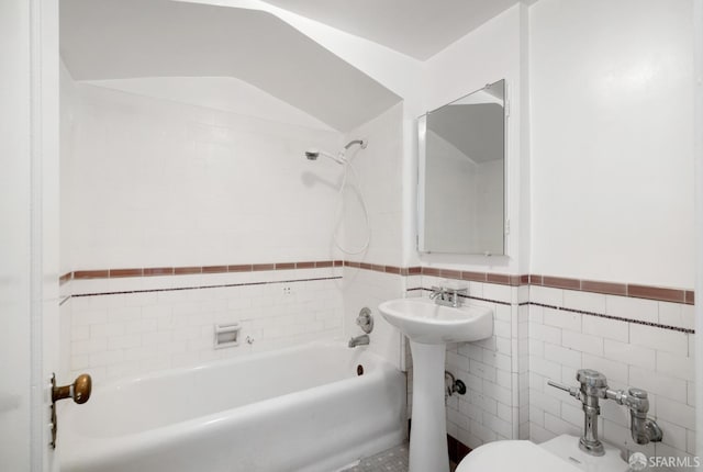 bathroom with tiled shower / bath combo, tile walls, and toilet