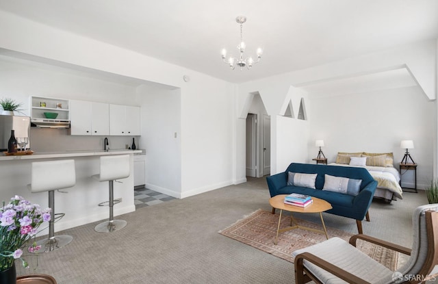 carpeted living room featuring sink and a notable chandelier