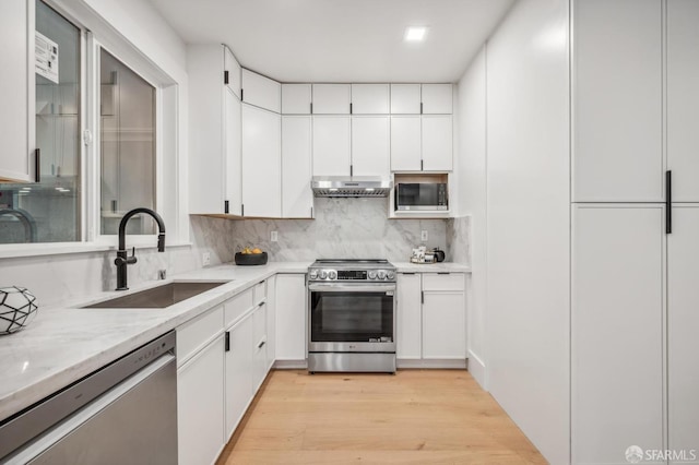 31 Romolo Pl Unit 1, San Francisco, CA 94133 - kitchen featuring stainless steel appliances, a sink, under cabinet range hood, light wood finished floors, and backsplash