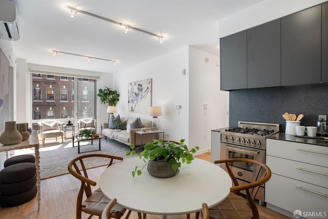 dining area with a wall mounted AC and light wood-type flooring